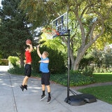 Lifestyle image of two children playing basketball, one of which is shooting the ball into the hoop