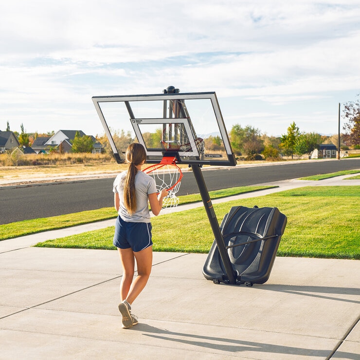 Lifestyle image shoiwng a woman moving the basketball hoop